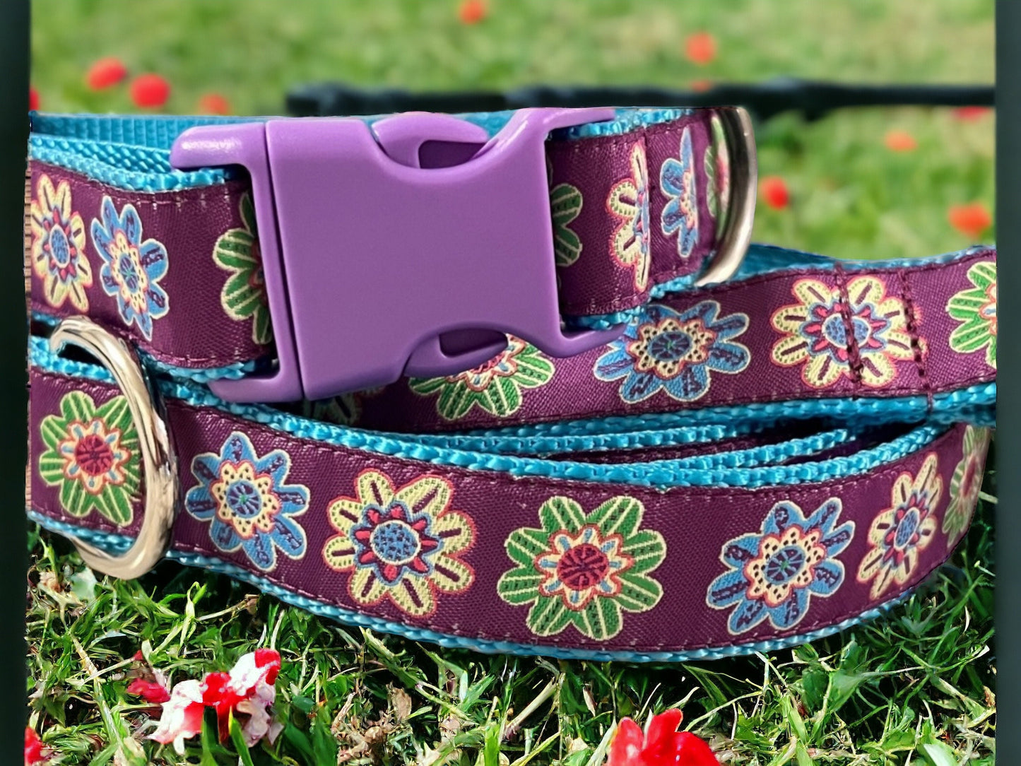 Purple collar with large bright colored flowers on it with a blue background and a purple buckle sitting on a green lawn